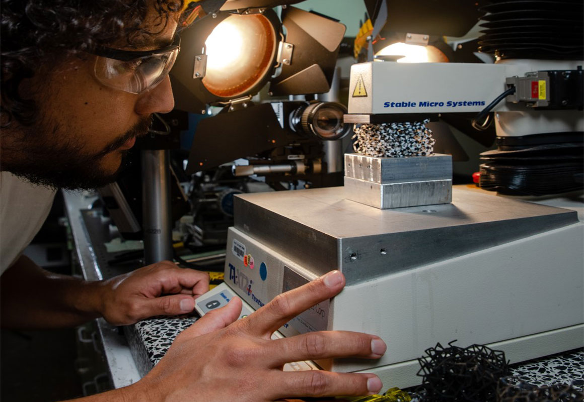 A man wearing safety goggles leans over a scientific device.