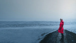 girl in red jacket looking in the distance on the foggy beach