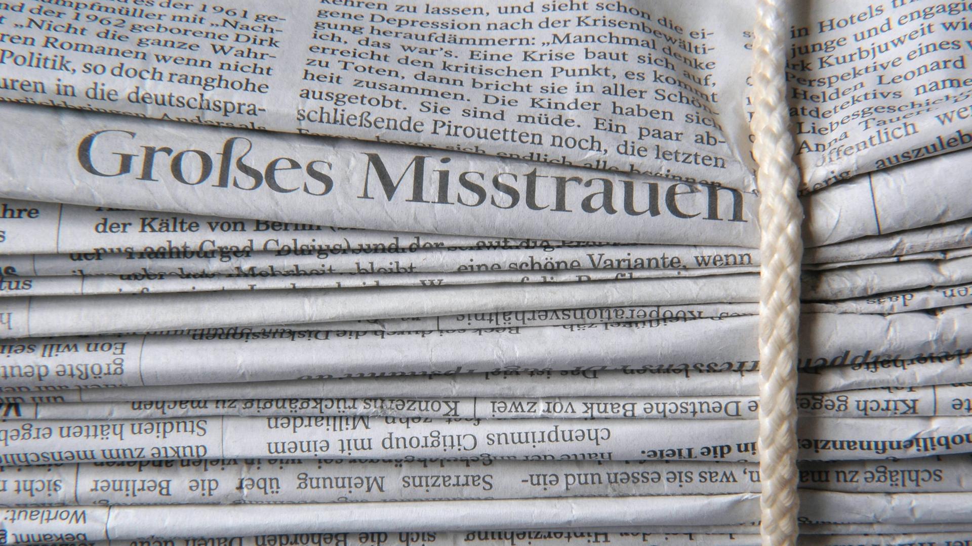 Gebündelter Zeitungsstapel mit Schlagzeile "Großes Misstrauen"