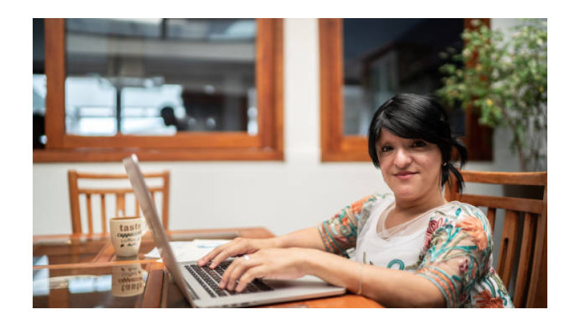 Woman using her computer with office as background.