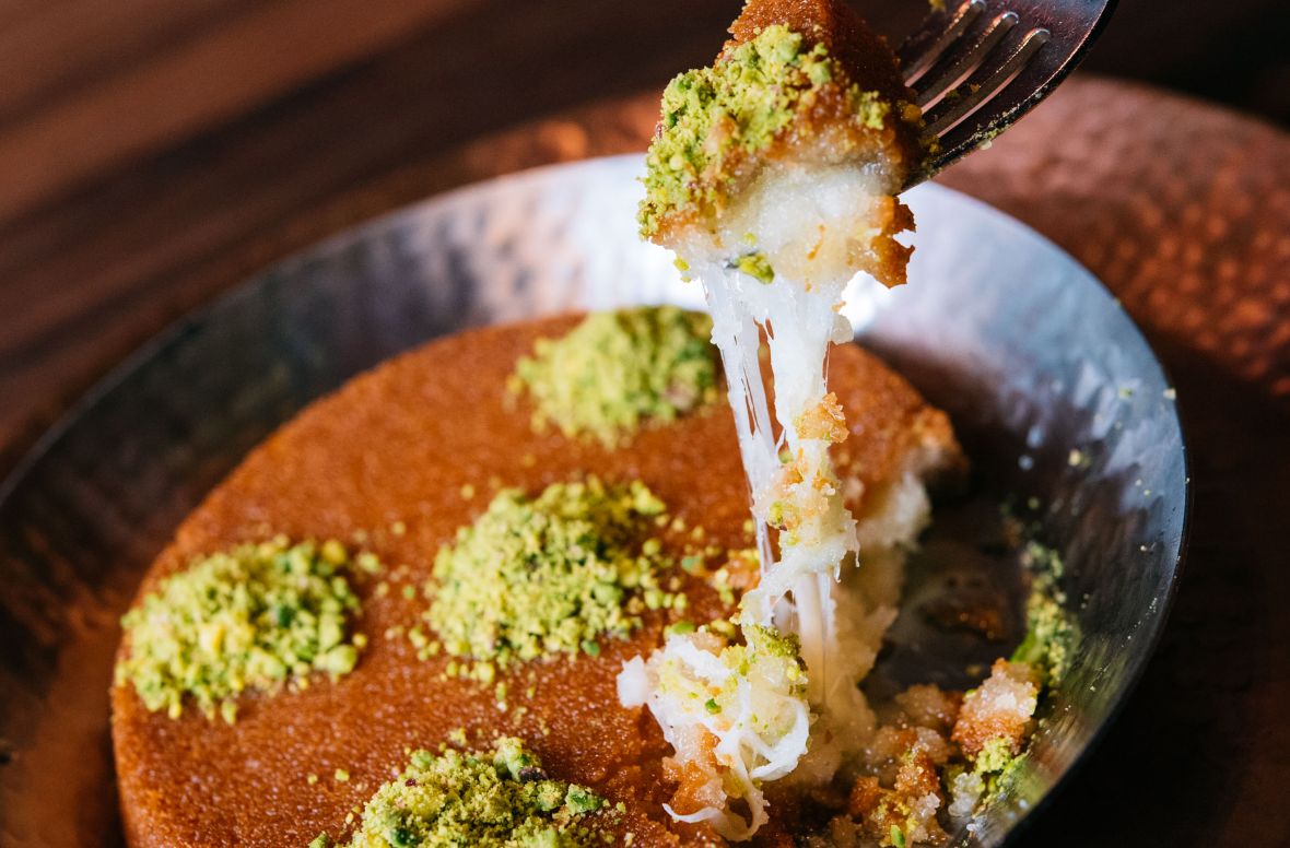 Kunafa in a bowl with a fork taking a piece out