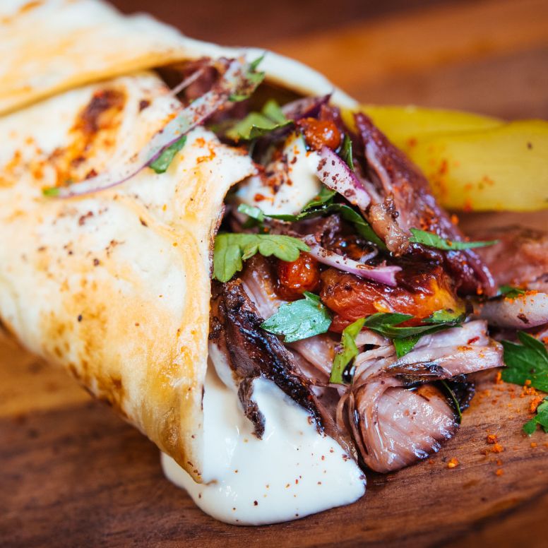 Shawarma Sando sitting on a wooden serving plate