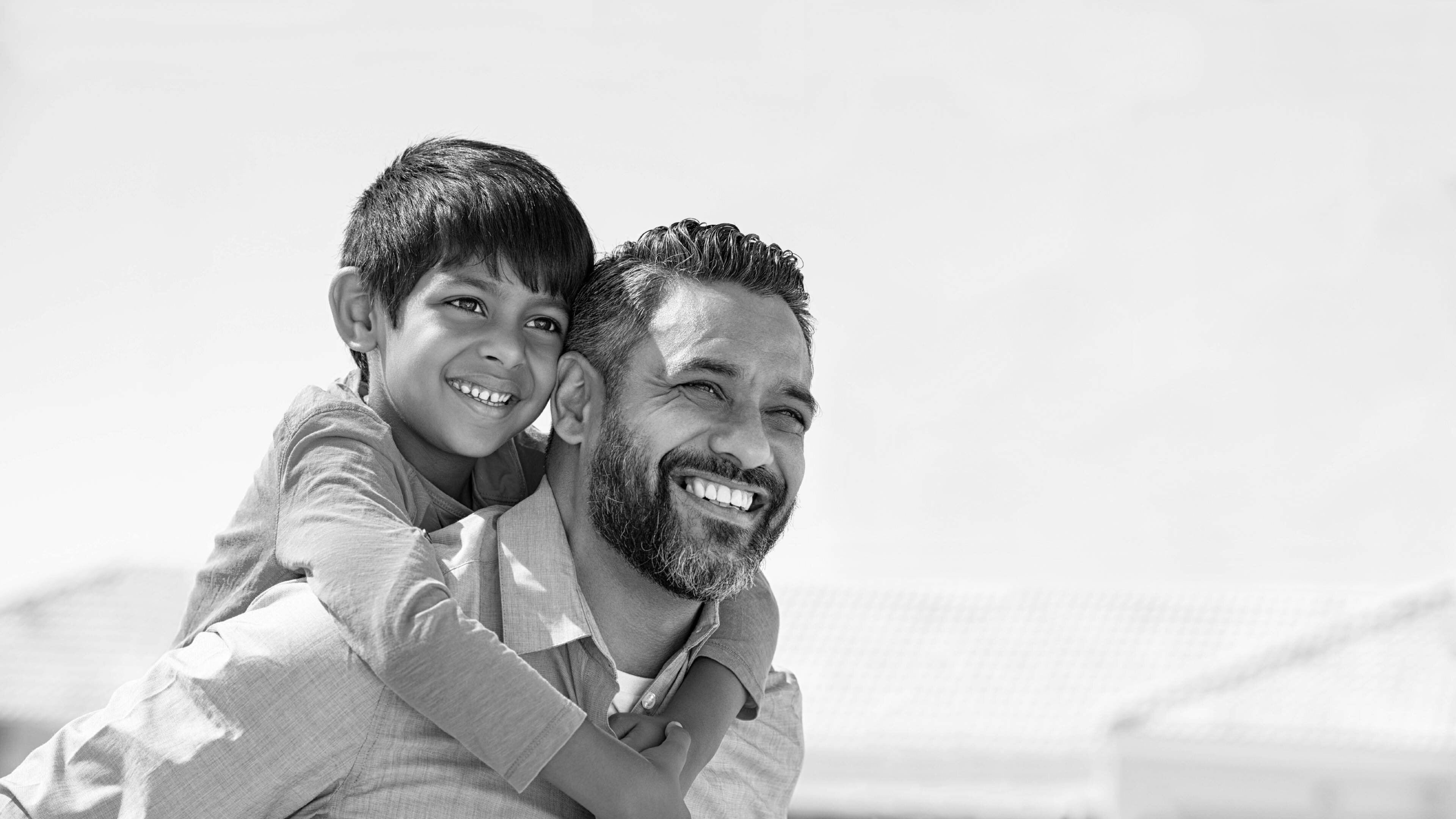 Smiling man carrying smiling child on his back.