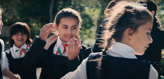 A group of young girls, wearing school uniforms, smiling during a break outdoors