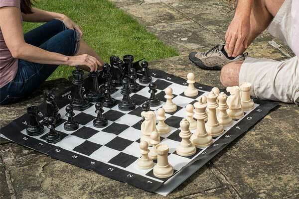 Two people playing a large outdoors chess set