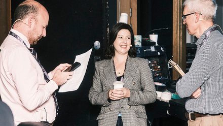 Two men and a woman have a conversation backstage