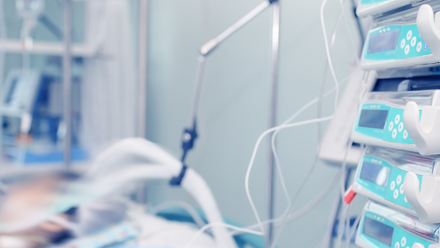 A hospital bed with a blurry patient hooked up to machines and monitors.