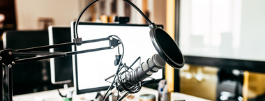 A radio microphone in front of multiple computer screens