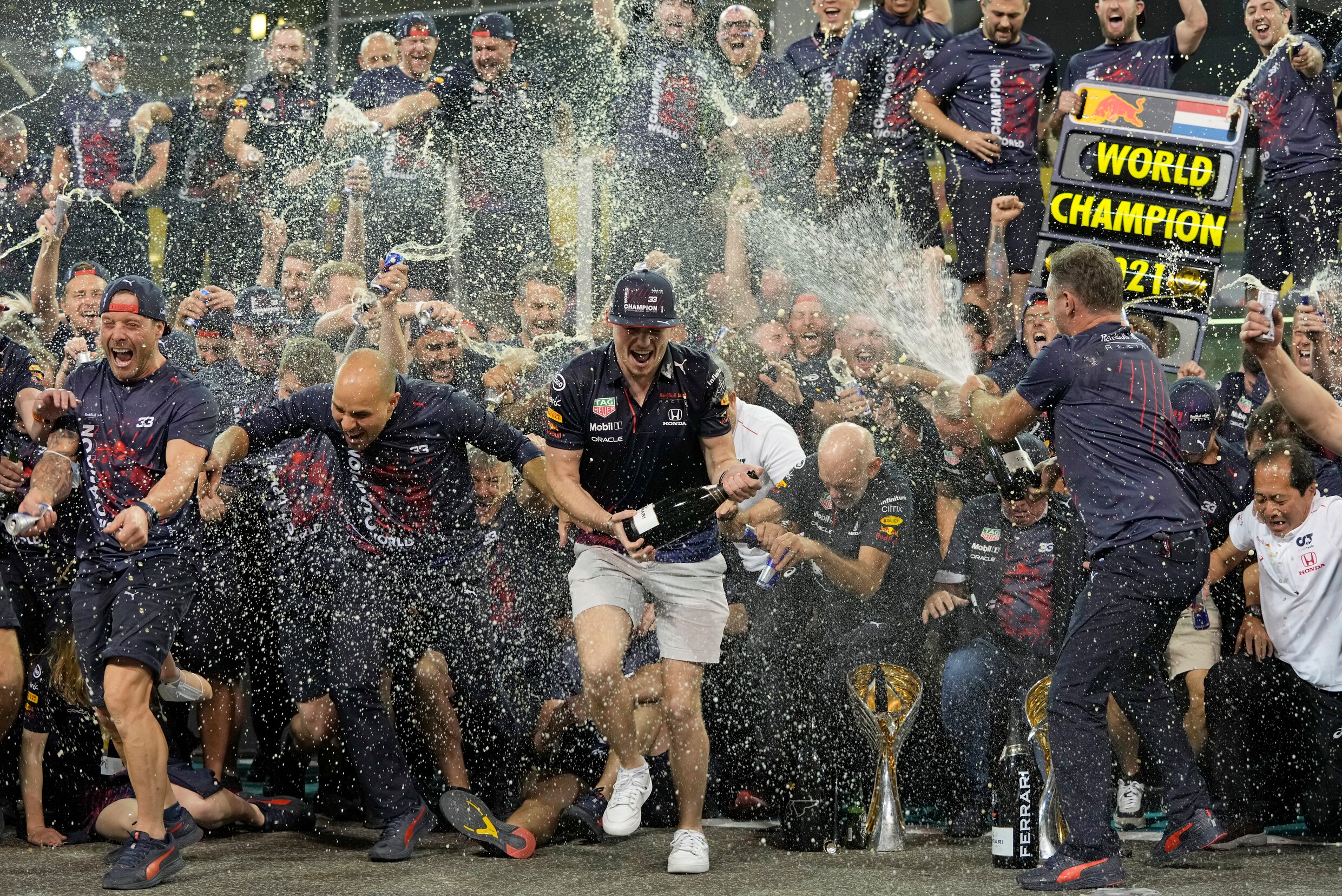 Teambaas Christian Horner van Red Bull (r) spuit Max Verstappen (m) nat met champagne.