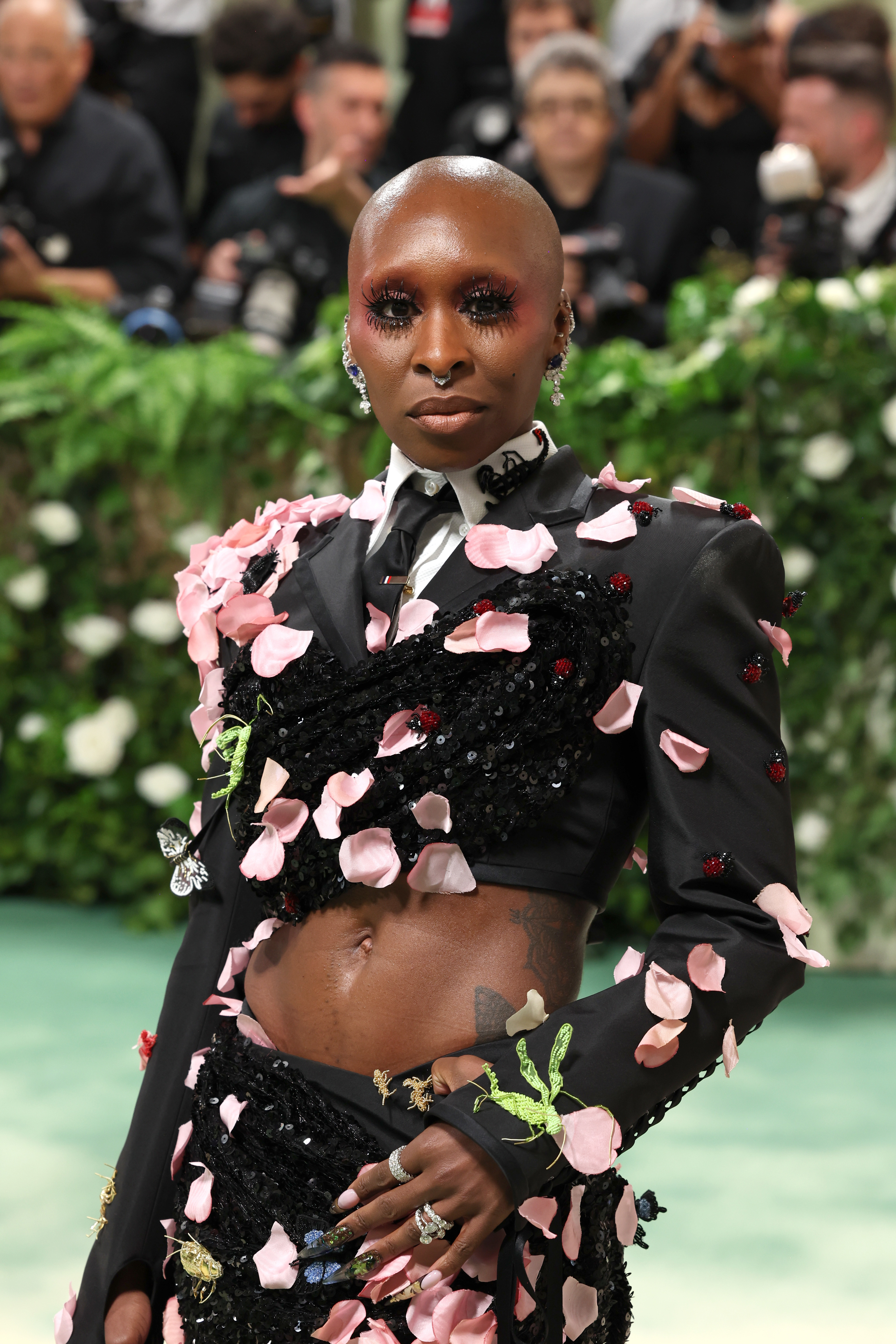 A person at a formal event wearing a floral-themed outfit embellished with petals and sequins