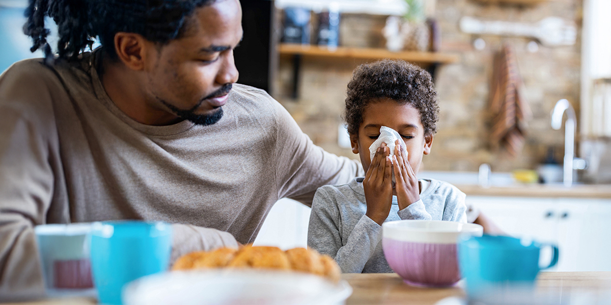 A father comforting his child as he blows his nose. 