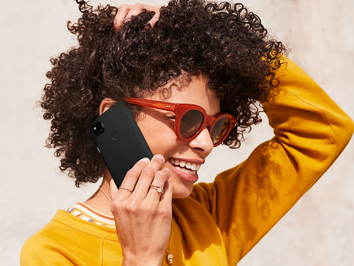 Side angle of a smiling woman from the shoulders up. She is using her smartphone.