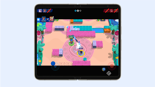 Two characters firing at each other in a colourful arena with pools and trees in Brawl Stars on a foldable phone's screen.