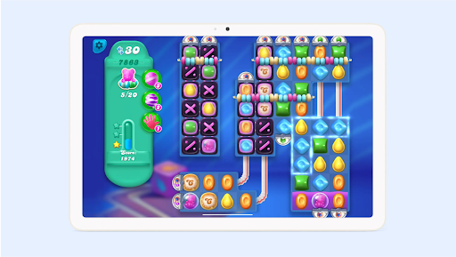 Um tablet mostrando o Candy Crush Soda Saga com canudos, doces e pontuação na tela.