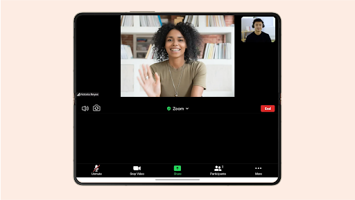 A foldable phone displaying a zoom call with 2 people smiling and talking to each other.