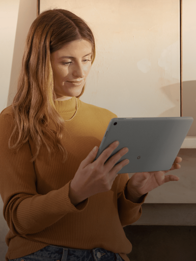 A lady smiling while looking at her tablet's screen.