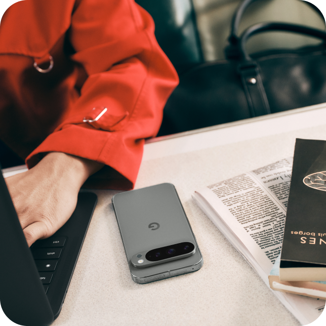 A person working on a laptop next to their Google Pixel phone.