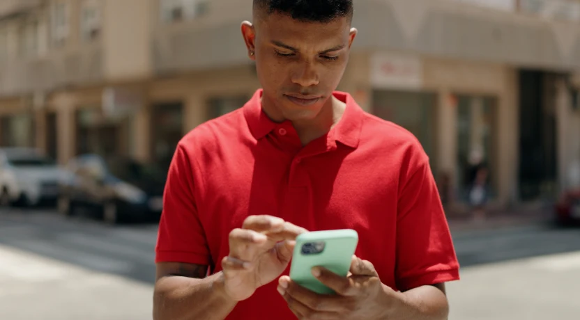 A young man looks intently at his smartphone screen