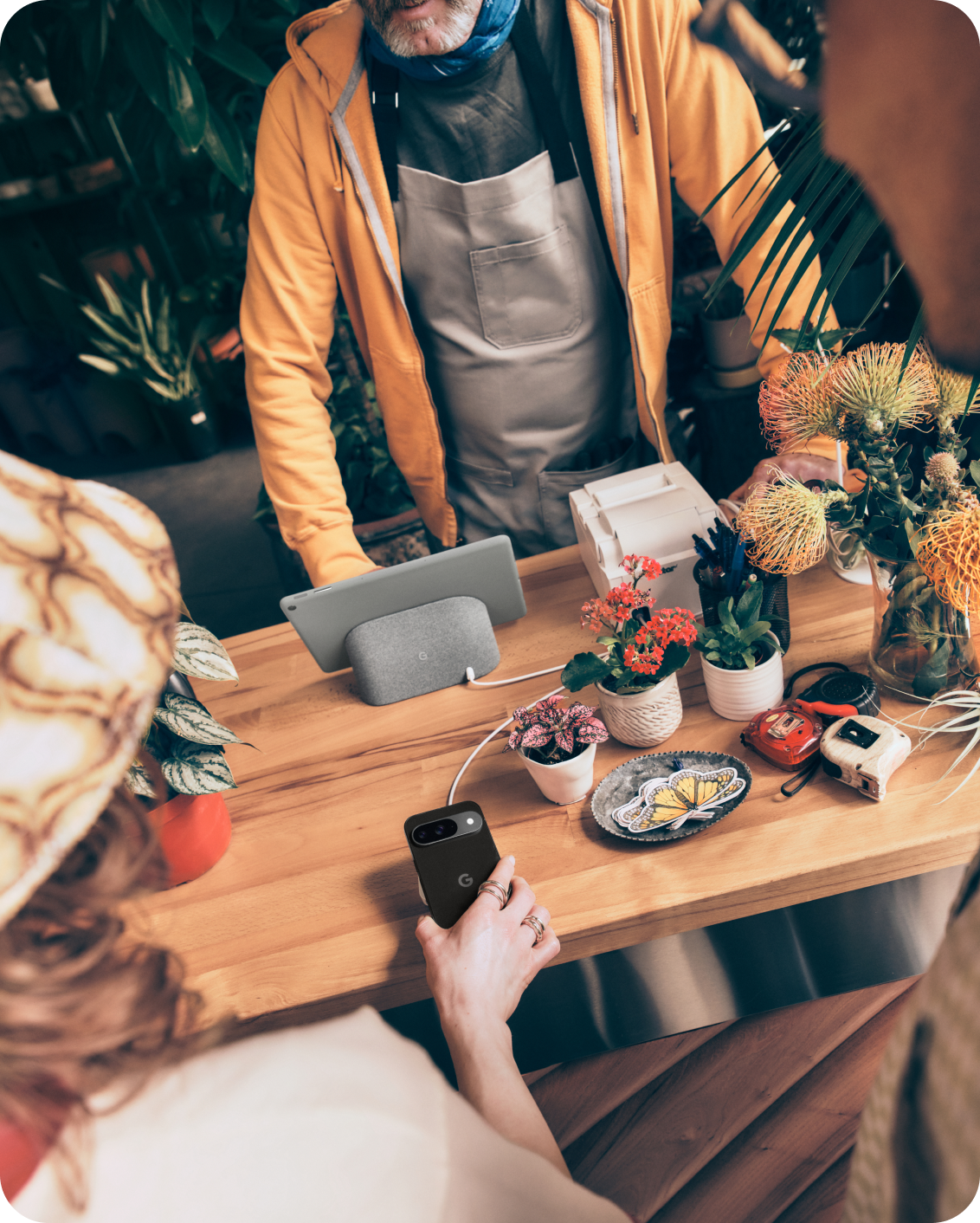 A man using a Google Pixel Tablet for his flower shop with a customer using her Google Pixel 9 phone.