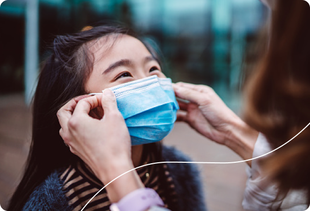 Adult putting mask on smiling young person