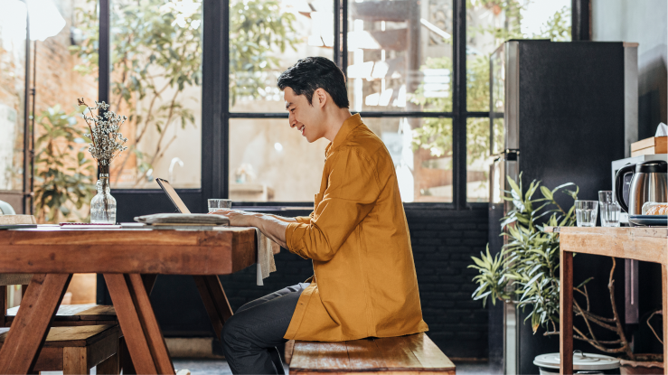 Eine Person sitzt mit einem Laptop am Schreibtisch und arbeitet. 