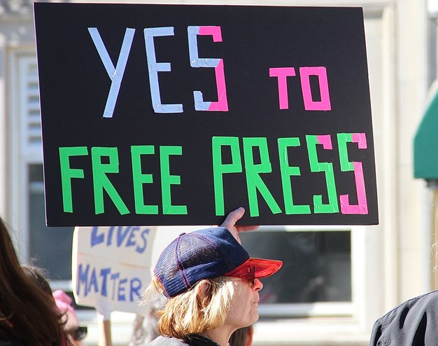 A woman holding a Yes to Free Press sign