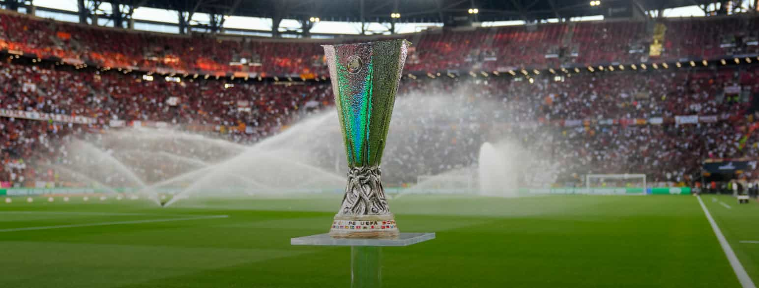 Et trofé av metall står på et podium ute på en fotballbane