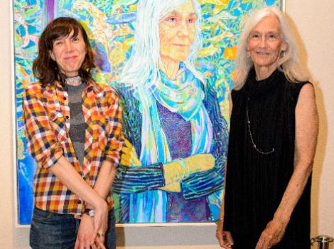 Two women standing in front of a portrait