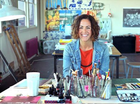 Woman seated in an artist's studio surrounded by painting materials