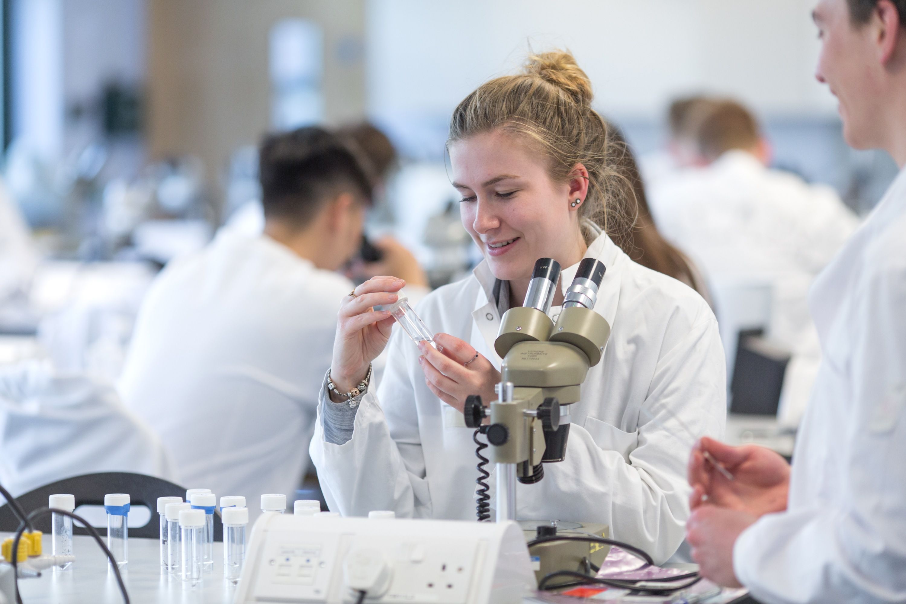 Biological Sciences student with microscope and pipette