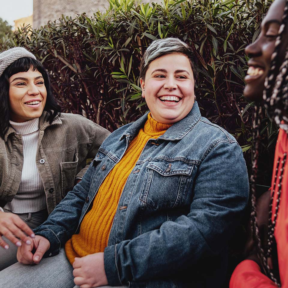 Interracial cheerful group of happy girls having fun talking together in the park talking and having fun sitting on a bench in the park 