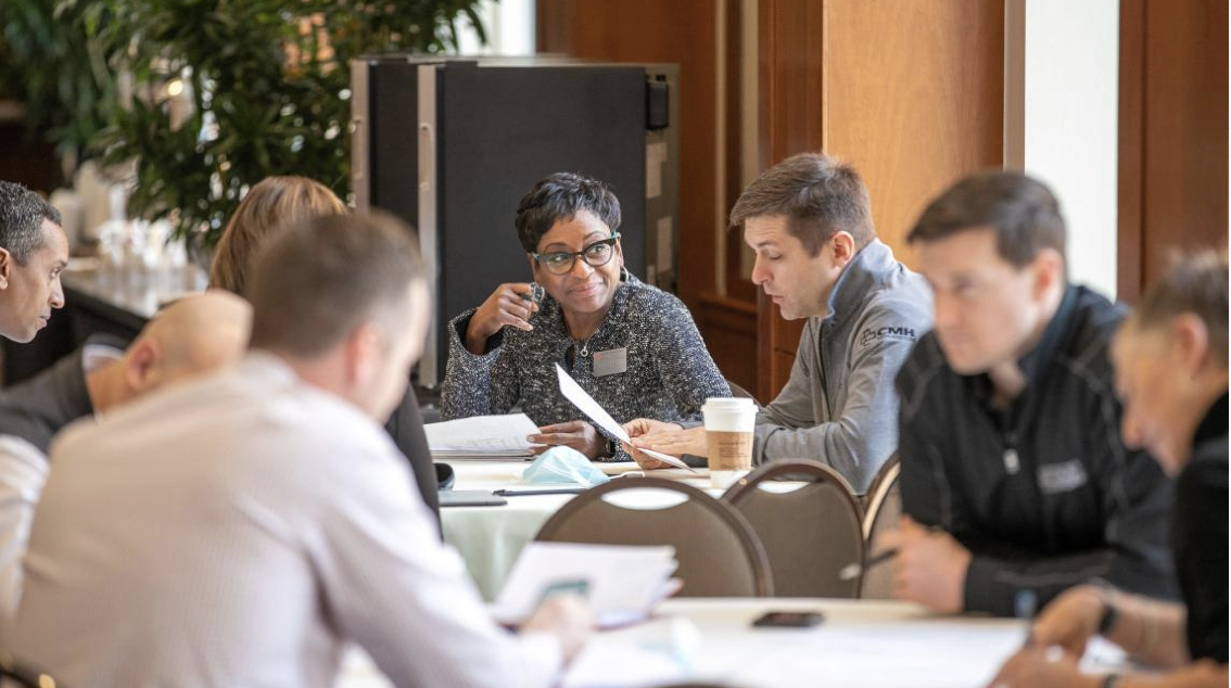 Group of students sitting at a table discussing a paper