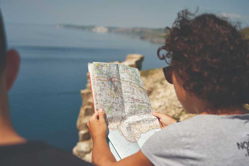 Person sat near the coast examining a paper map