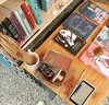 A close-up photo of a table displaying books, a mug, stationery, and other items