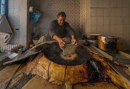 Beignet Maker in Kairouan Tunisia, I am nominating it as FP because in this picture he is sitting as in mdtitation in front of the wok and he is moving a beignet with another one to make place :)