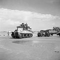 Sherman BARV tows a disabled Bedford articulated lorry and trailer off the beach.