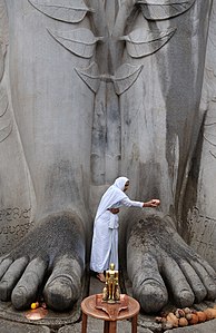 A Jain elderly woman washes the feet of Bahubali Gomateswara at Shravanabelagola, Karnataka, India.