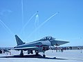 One Eurofighter Typhoon in Getafe air base under an espectacular flight of the Patrulla Águila.