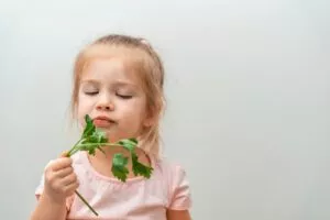 Et nærbillede af en lille pige der spiser koriander og ser utilfreds ud.