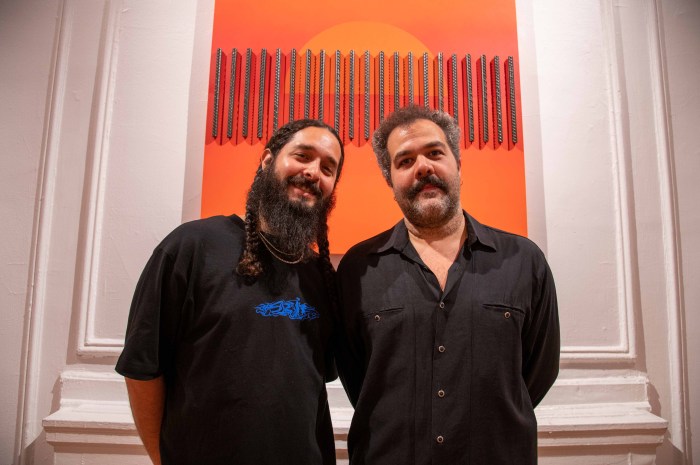 Artists Yiyo Tirado and Charlie Quezada pose in front of one of Tirado's pieces for their new exhibit, "Hora Caribe" at the Andrew Freedman Home on Grand Concourse.