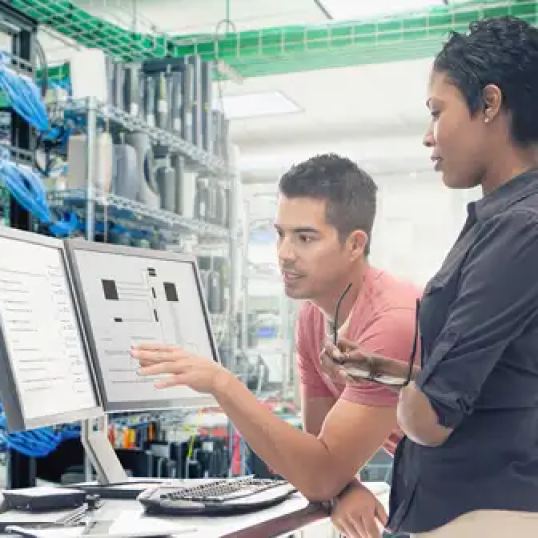 Two men working together in front of a computer detailing manufacturing information for 4XEM.