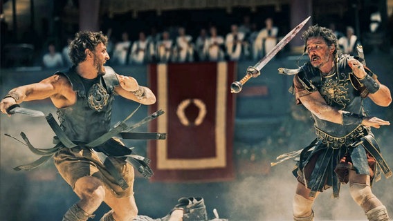 Zwei Gladiatoren in einer Arena im Lederoutfit kämpfen miteinander - Szene mit Paul Mescal (links) und Pedro Pascal aus "Gladiator II" von Ridley Scott © Paramount Pictures Germany 