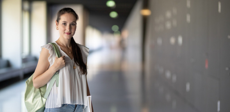 Friendly student is standing in the aisle of the Weinhold building